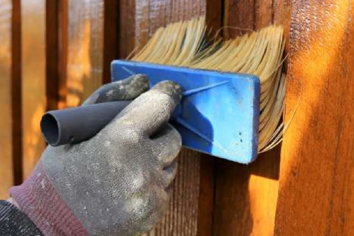 Hand trägt Lasur mit einem Pinsel auf